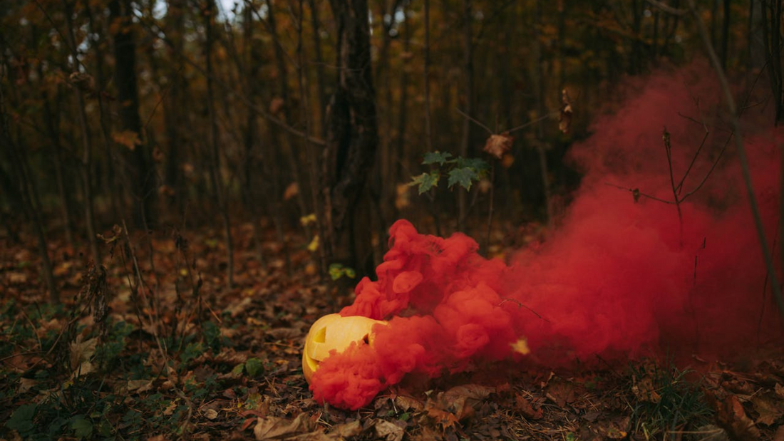 Halloween pumpkin in the woods, with plumes of red smoke rising from it.